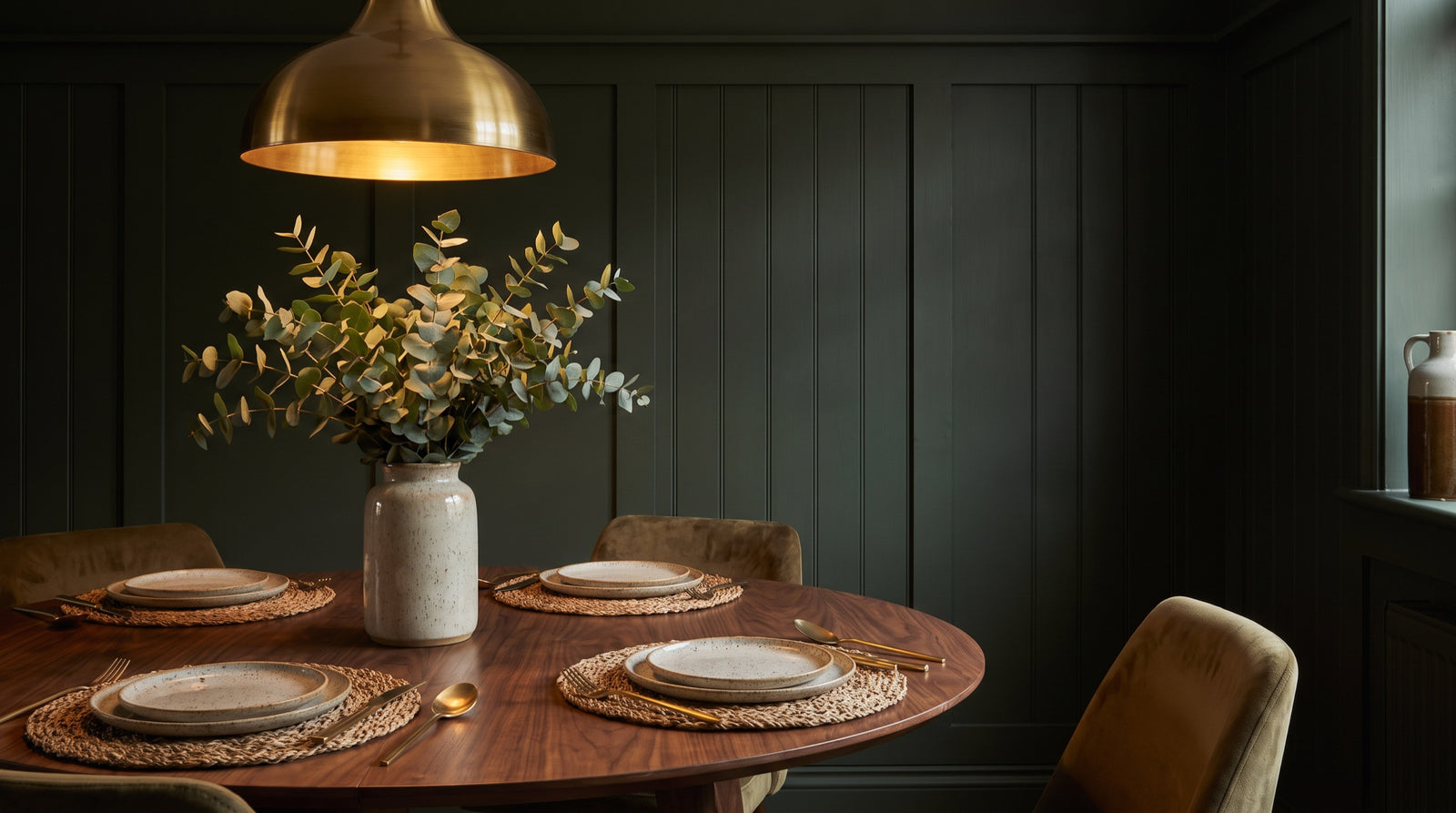 Dining corner with a brass pendant light and stoneware place settings